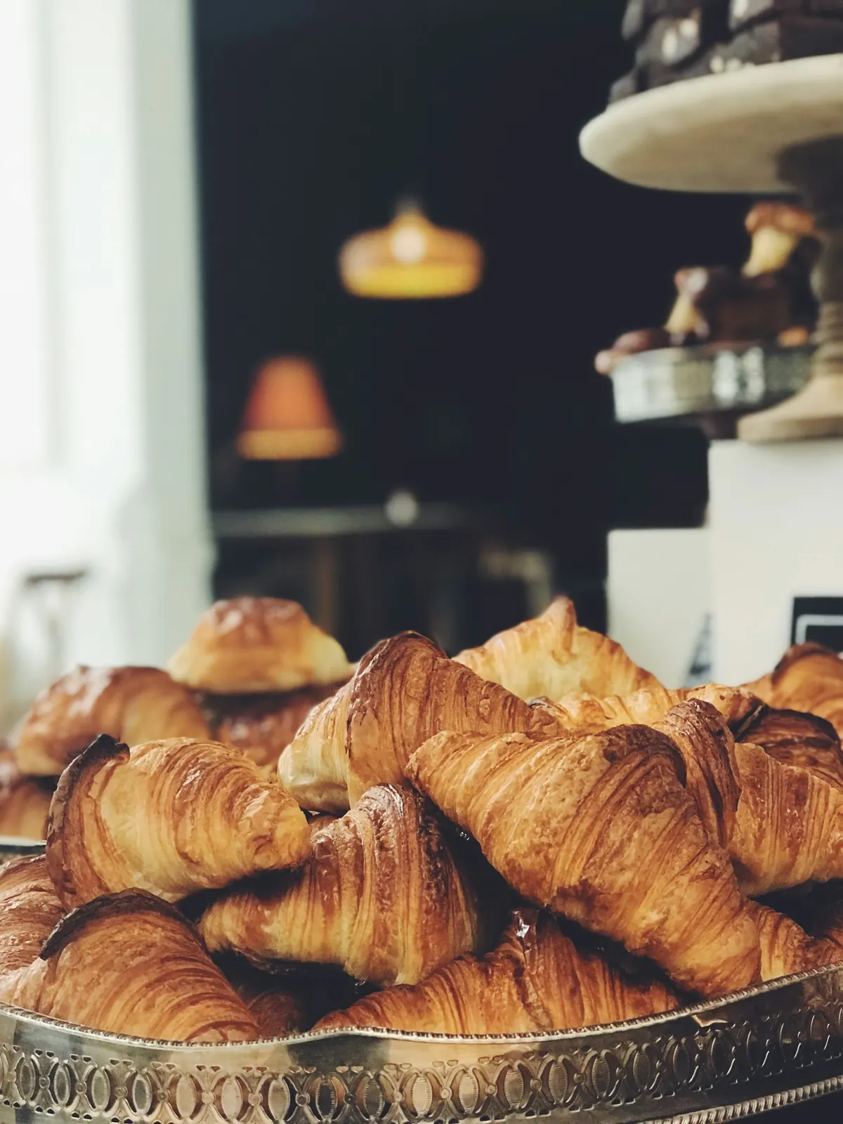 medialunas apiladas en una fuente sobre el mostrador del café